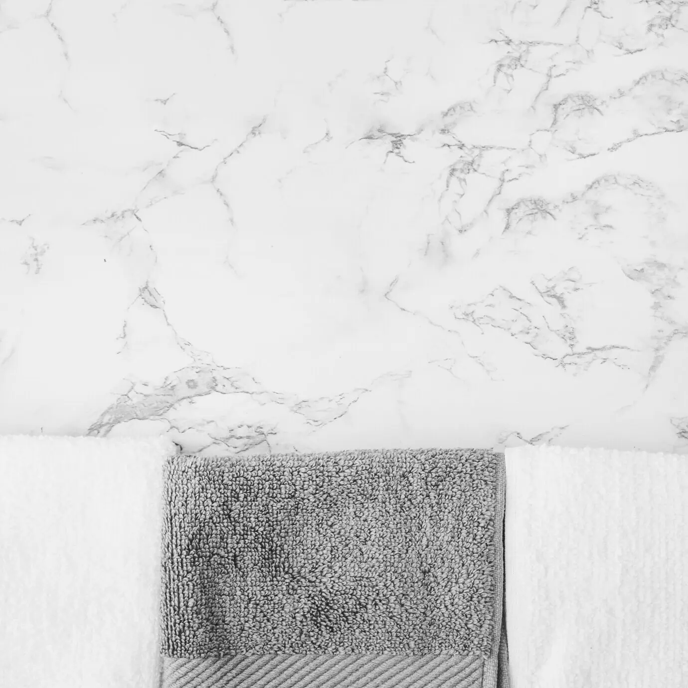 Schwarze und weiße Handtücher vor einem Marmorhintergrund